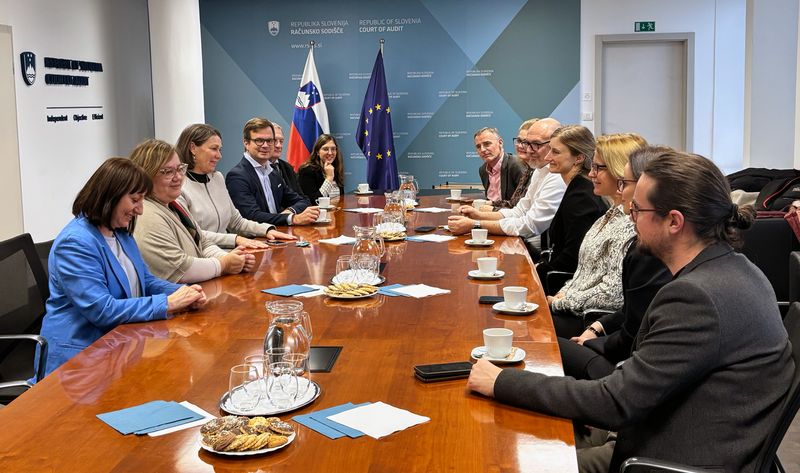 Skupina udeležencev, vključno s predsednico računskega sodišča Republike Slovenije, Jano Ahčin, ter vrhovnima državnim revizorkama Jernejo Vrabič in Heleno Jenko, sedi za konferenčno mizo na sedežu računskega sodišča v Ljubljani