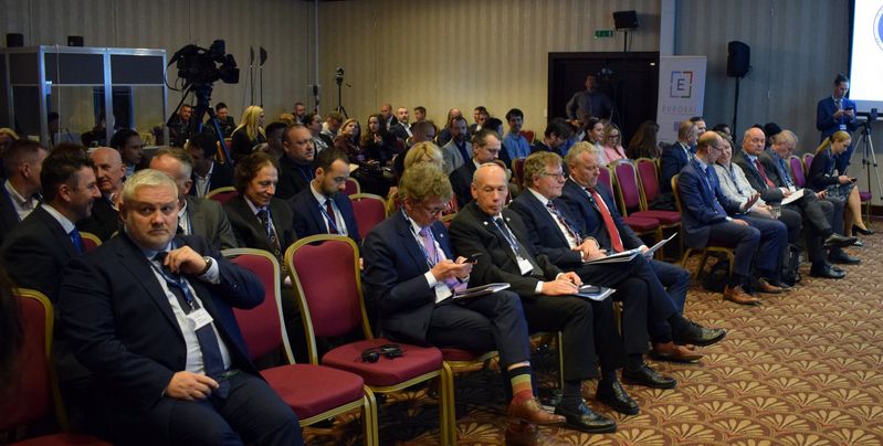 Udeleženci mednarodne konference sedijo v konferenčni dvorani in spremljajo program dogodka. Med občinstvom so predstavniki vrhovnih revizijskih institucij, državnih ustanov in drugih organizacij, v ozadju pa je vidna snemalna oprema ter pano organizacije EUROSAI.