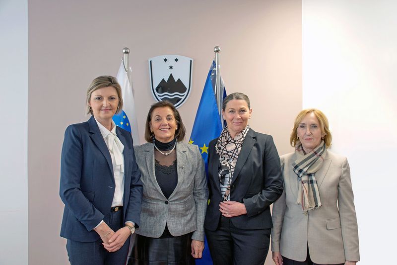 Predsednica Računskega sodišča Republike Slovenije Jana Ahčin in namestnica glavnega državnega revizorja VRI Hrvaške dr. Nediljka Rogošić z delegacijo ob skupnem fotografiranju v prostorih Računskega sodišča Republike Slovenije; v ozadju so vidni grb Republike Slovenije ter zastavi Slovenije in Evropske unije.