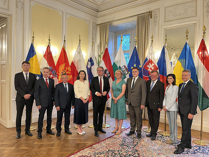 Skupinska fotografija vodij vrhovnih revizijskih institucij skupine držav V4+2 in letošnjih VRI opazovalk v Graškem gradu pred državnimi zastavami