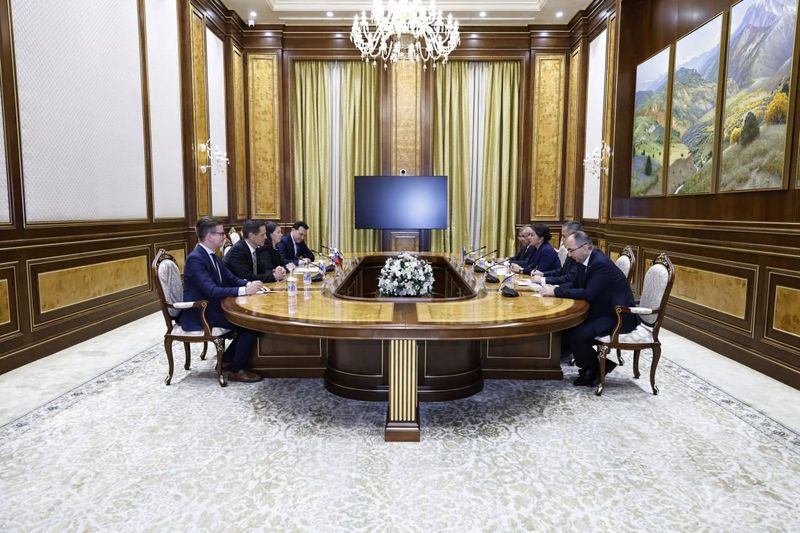 Delegaciji Slovenije in Uzbeksitana sedita nasproti za veliko ovalno mizo v razkošno opremljeni sobi Senata Republike Uzbekistan. Na sredini mize je cvetlični aranžma, nad mizo visi velik lestenec. Na stenah so slike pokrajine, za udeleženci pa visoke zavese.