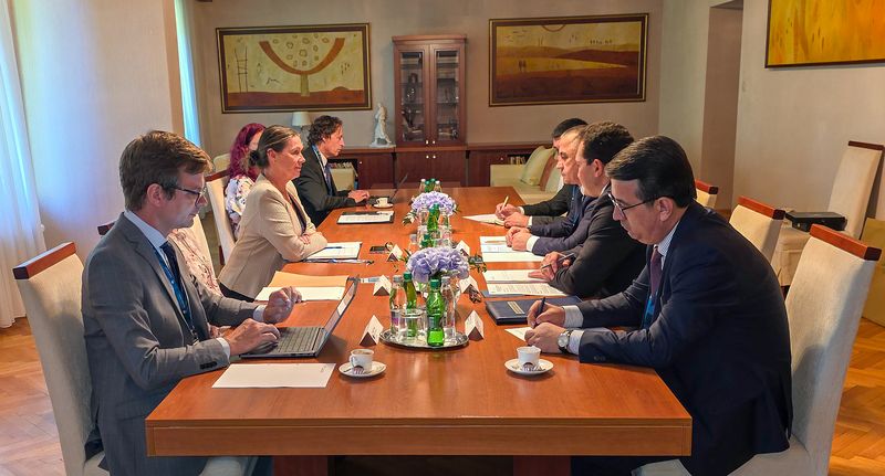 Delovno srečanje med delegacijama Računskega sodišča Republike Slovenije in VRI Uzbekistana Delovno srečanje med delegacijama Računskega sodišča Republike Slovenije in VRI Uzbekistana. Predstavniki obeh delegacij sedijo drug nasproti drugega za dolgo konferenčno mizo z dokumenti, prenosnimi računalniki, zapiski in pijačo.