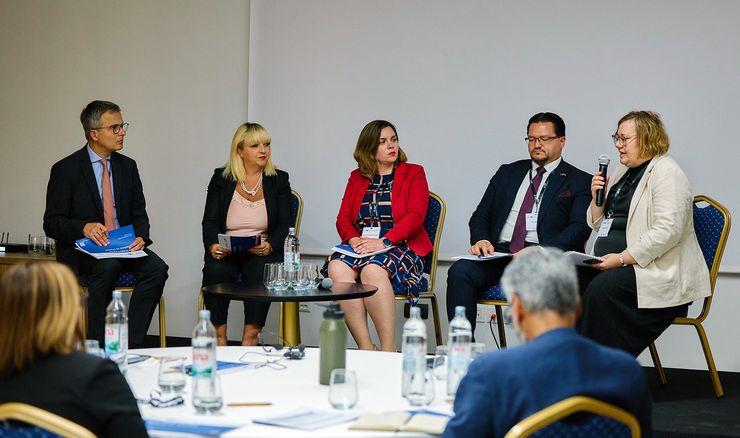 Pet udeležencev sedi v polkrogu med panelno razpravo na konferenci, ki sta jo v Zagrebu organizirala Center za razvoj financ (CEF) in britanski inštitut CIPFA. Udeleženci razpravljajo o preglednosti porabe evropskih sredstev; Jerneja Vrabič uporablja mikrofon.