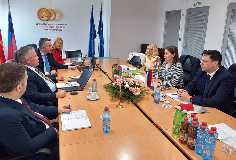 Na fotografiji delovnega sestanka na sedežu VRI Severne Makedonije v Skopju sta delegaciji VRI Severne Makedonije in računskega sodišča, ki sedita v sejni sobi med delovnim pogovorom.