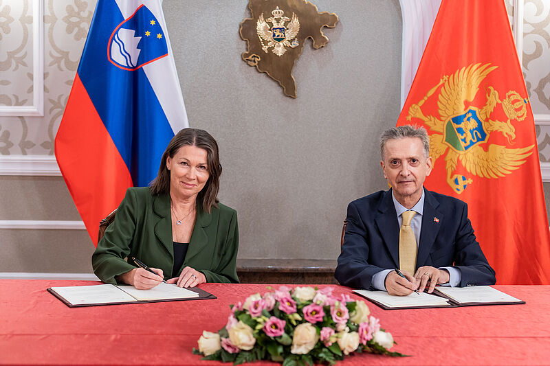Predsednica računskega sodišča Jana Ahčin in predsedujoči senatu vrhovne revizijske institucije (VRI) Črne gore, senator Nikola N. Kovačević ob podpisovanju sporazuma za svečano mizo pred zastavama Slovenije in Črne gore