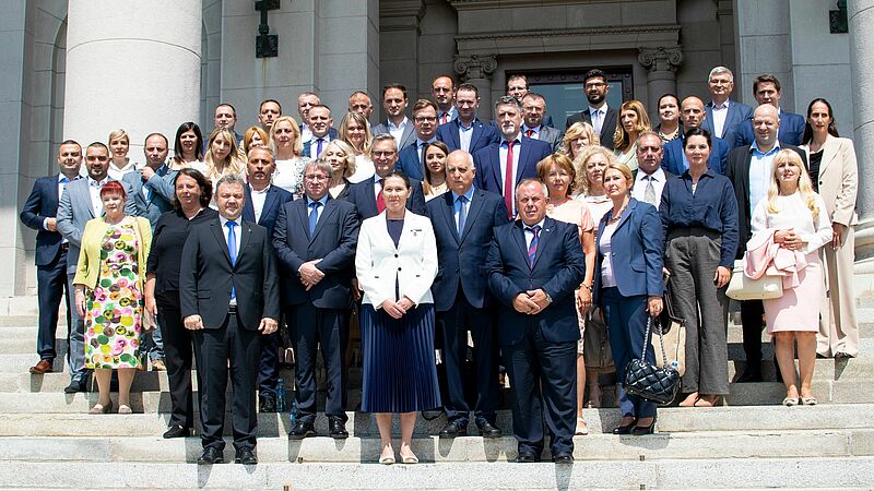 The conference participants are standing on the steps in front of the entrance to the National Assembly building in Belgrade.
