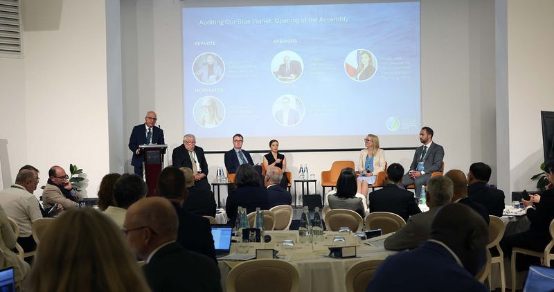 Generalni revizor Malte Charles Deguara nagovarja udeležence ob odprtju skupščine INTOSAI WGEA; ob njem sedijo osrednji govorci in panelisti prve razprave