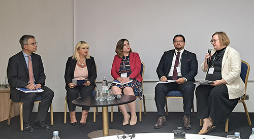 Pet udeležencev sedi v polkrogu med panelno razpravo na konferenci, ki sta jo v Zagrebu organizirala Center za razvoj financ (CEF) in britanski inštitut CIPFA. Udeleženci razpravljajo o preglednosti porabe evropskih sredstev; Jerneja Vrabič uporablja mikrofon.